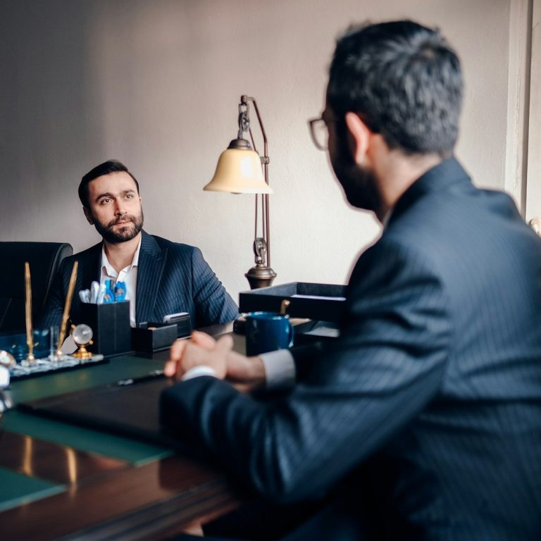 Proximité : écoute et accompagnement personnalisé chez VILA’GENCIS Consultation professionnelle entre deux hommes en costume, illustrant l’écoute et l’accompagnement sur mesure